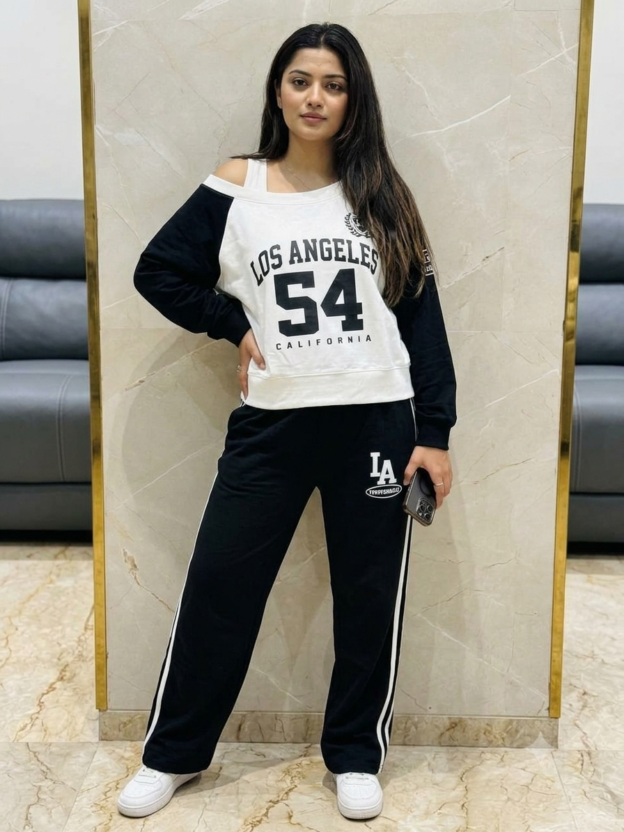 Model wearing a white and black Los Angeles 54 long-sleeve top with a shoulder cutout and matching black wide-leg trousers with white side stripes