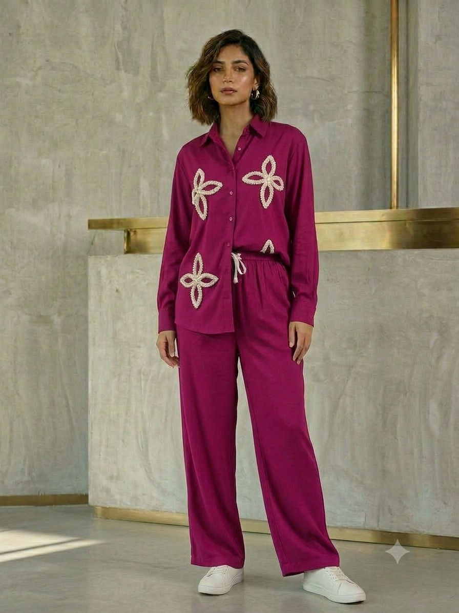 Model wearing a fuchsia long-sleeve button-front shirt with cream petal-shaped embellishments and matching wide-leg drawstring trousers